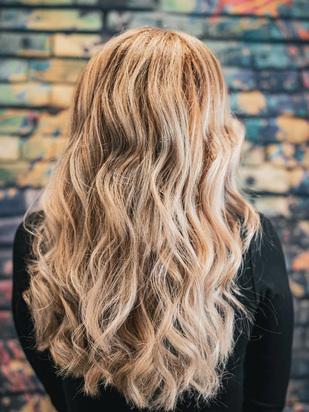 Dlhé vlasy s blond balayage pred farebnou stenou salóna